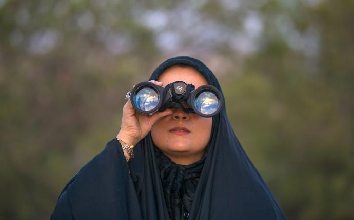 En kvinna med sjal tittar i en kikare