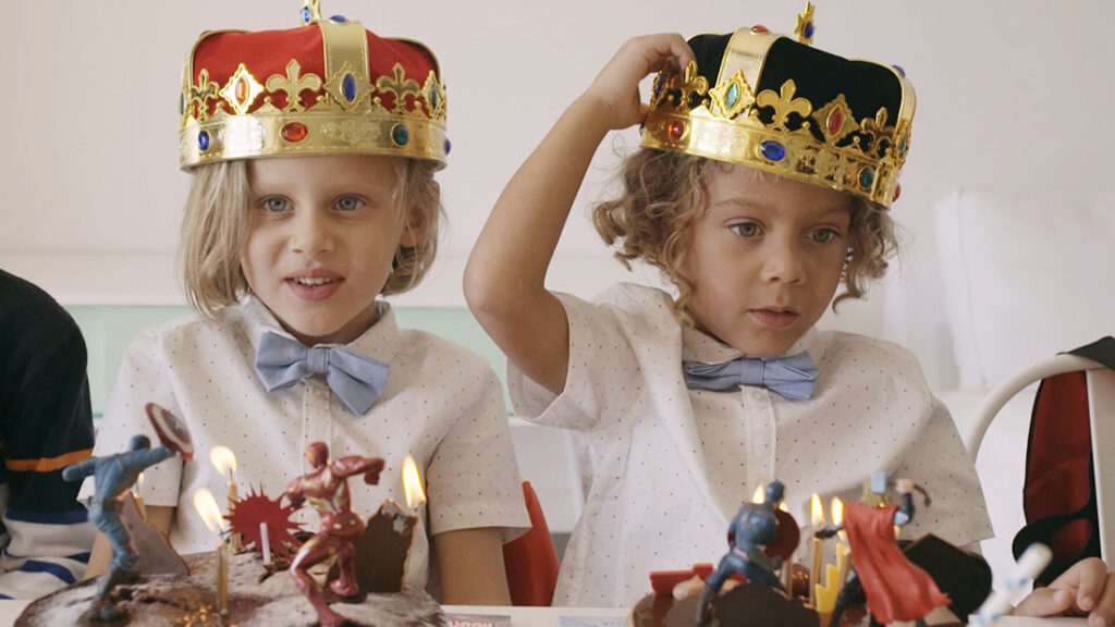 Två barn med kungakronor på kalas.