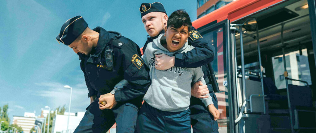 En liten kille är tagen av två poliser.