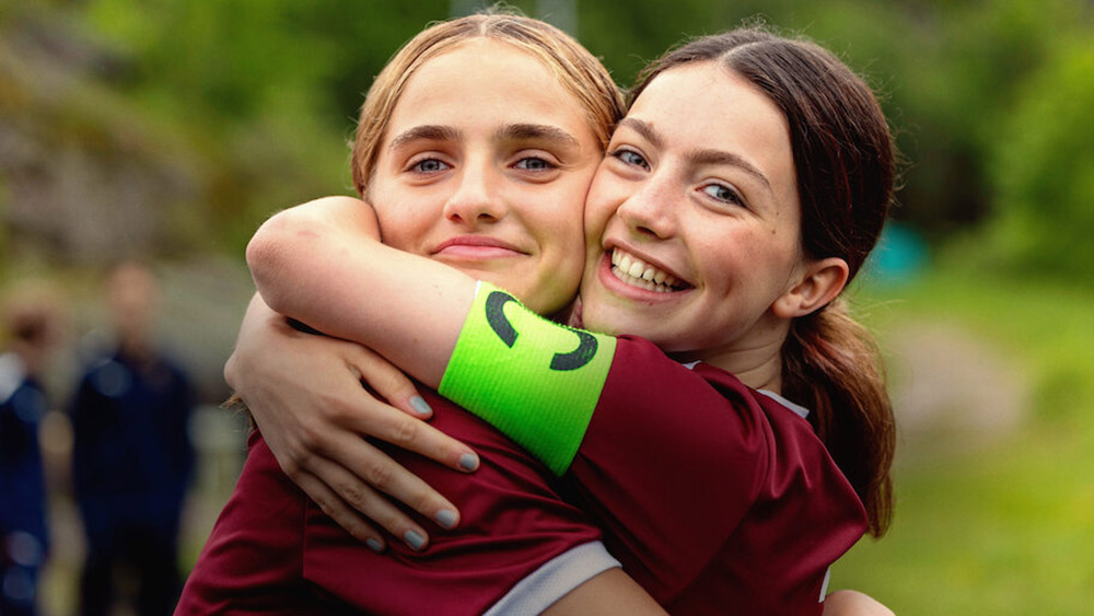 Två tjejer i sportkläder kramar varandra.