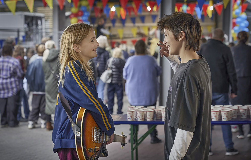 En tjej med gitarr och en kille pratar med varann.