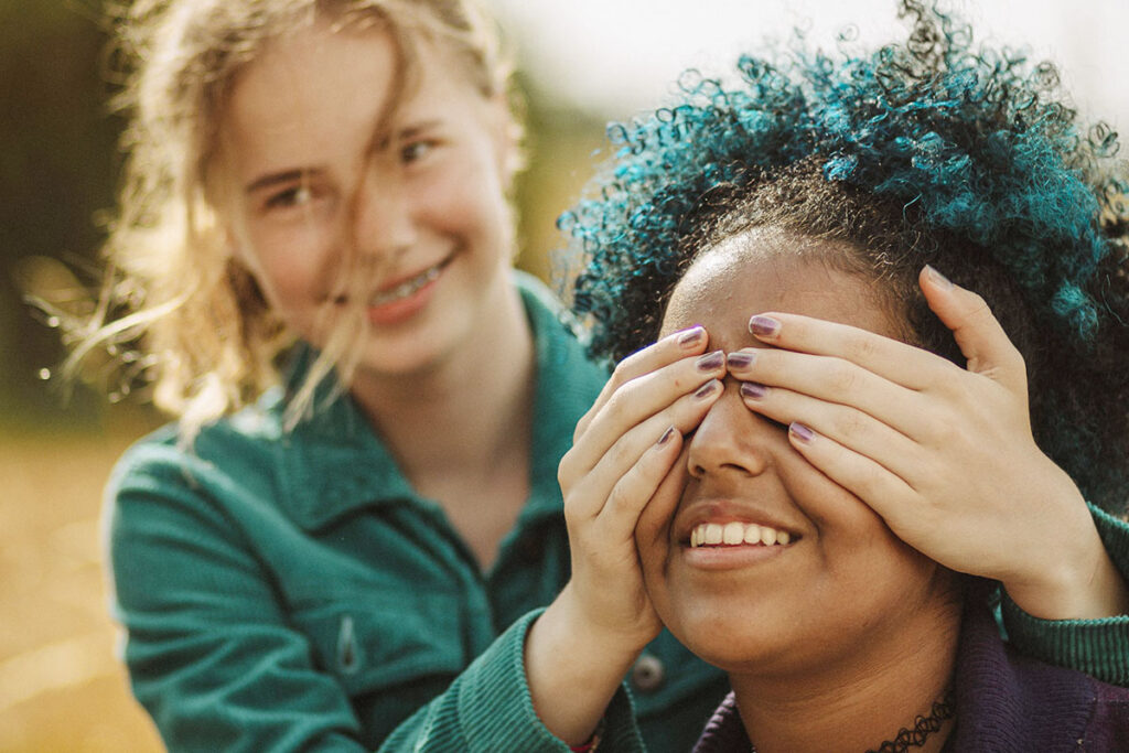 Två unga tjejer, den ene håller för för ögonen på den andre.