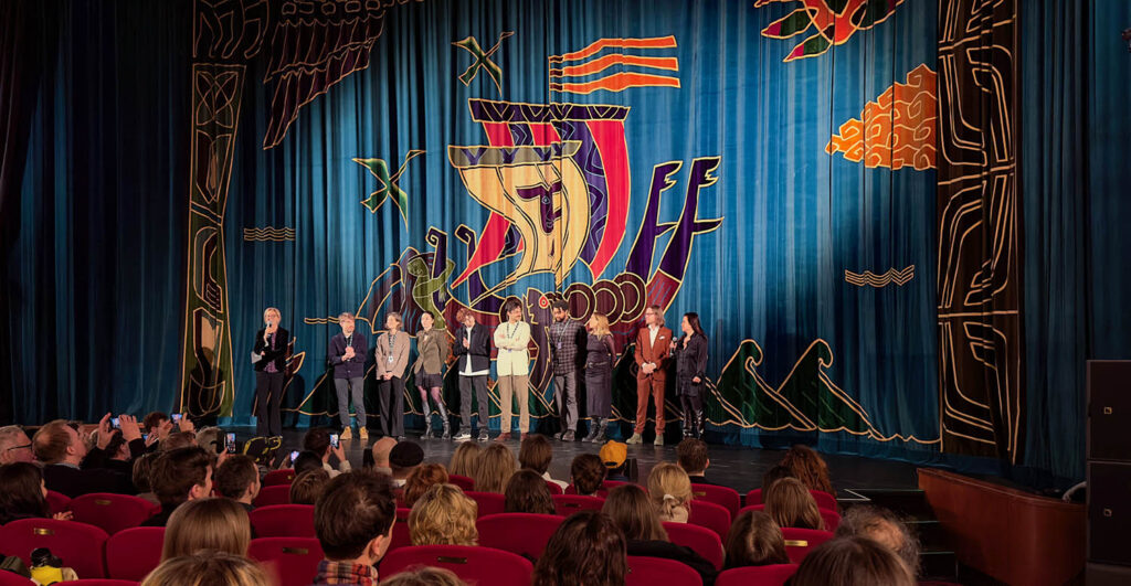 Kvinnor och män uppradade på en biografscen.